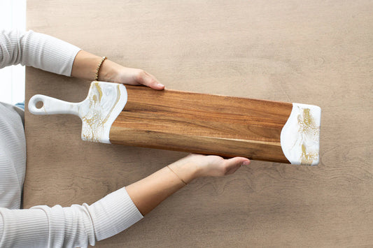 Lynn & Liana Baguette Acacia Board with white resin handles, held horizontally, close-up detail view