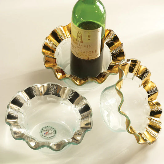 Annieglass Ruffle Wine Coasters in clear glass with gold-foil ruffled edges holding wine bottle