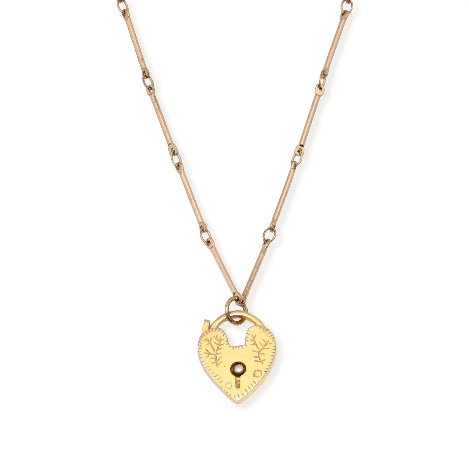 The Leslie Curtis Genesis Necklace by Leslie Curtis is a gold chain necklace with a heart locket pendant, featuring engraved details and a small keyhole at the center, complete with an extender for adjustable length.