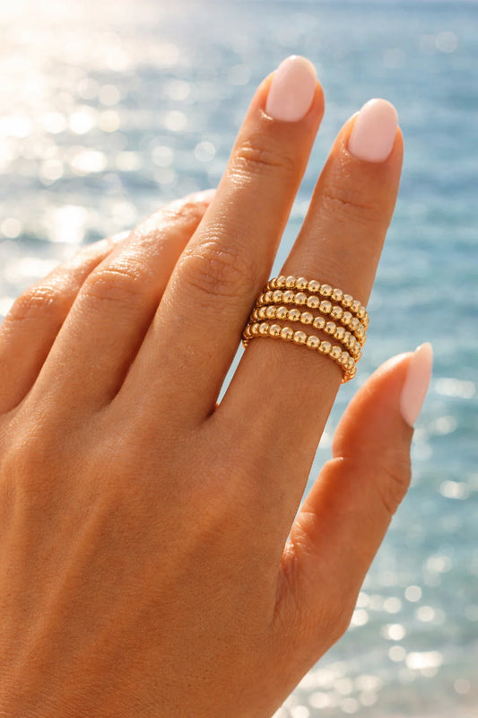 Coastal Grit Spring Ring Size 6 with stacked gold beaded bands worn on hand by ocean