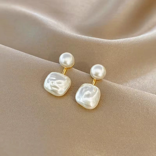 Coastal Grit Aura Baroque Studs with white baroque pearl drops and gold posts on neutral fabric