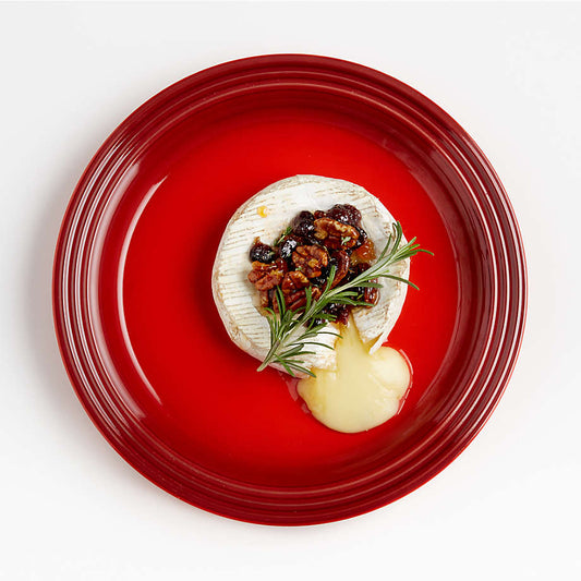 Le Creuset cerise dinner plate styled with cheese, herb, and food presentation