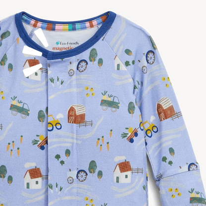 Introducing the Magnetic Me "Farm to Cradle" Magnetic Convertible Coverall, a light blue sustainable modal baby onesie from Magentic Me. Featuring delightful farm-themed prints including barns, tractors, trucks, trees, carrots, and houses, this coverall is designed with magnetic closures at the neckline and front for easy and fuss-free changes.