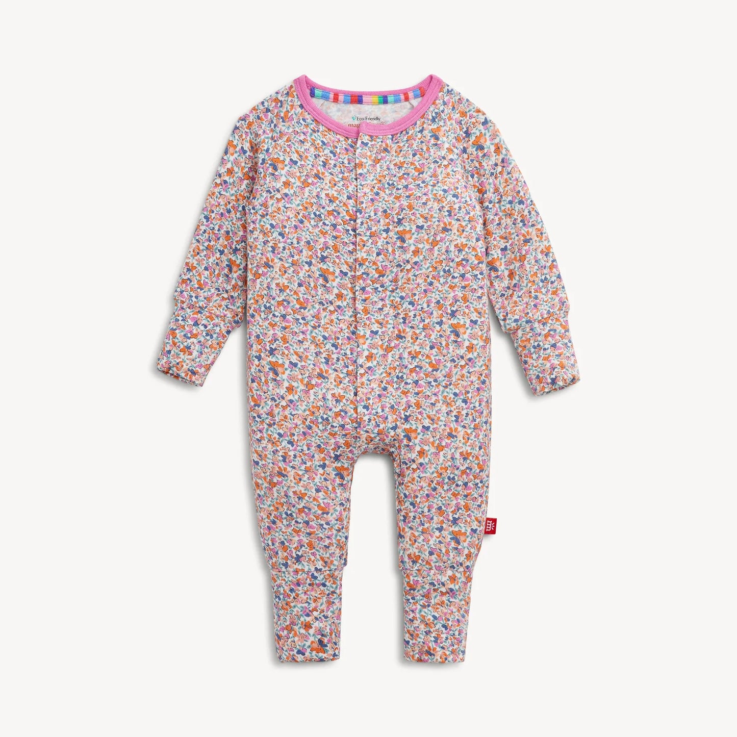Magnetic Me "Stella" Magnetic Convertible Coverall by Magnetic Me, featuring a floral pattern with long sleeves and legs, a pink collar, convenient front zipper closure, and a red logo tag on the left leg. The garment is displayed flat against a white background.