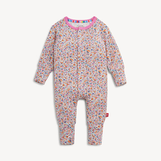 Magnetic Me "Stella" Magnetic Convertible Coverall by Magnetic Me, featuring a floral pattern with long sleeves and legs, a pink collar, convenient front zipper closure, and a red logo tag on the left leg. The garment is displayed flat against a white background.