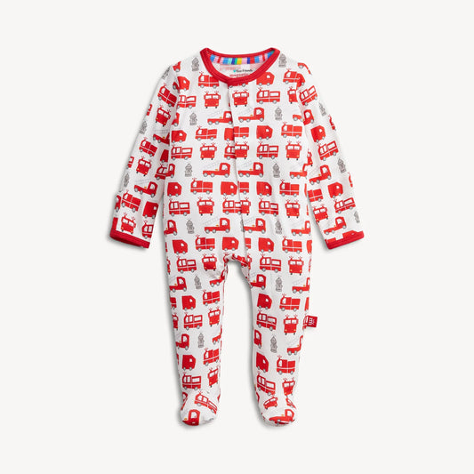 The Magnetic Me "Fired Up" Footie by Magnetic Me is a long-sleeve baby onesie adorned with red fire trucks, fire hydrants, and firefighters on a white background. It features convenient magnetic closures and has red trim around the collar and wrists.