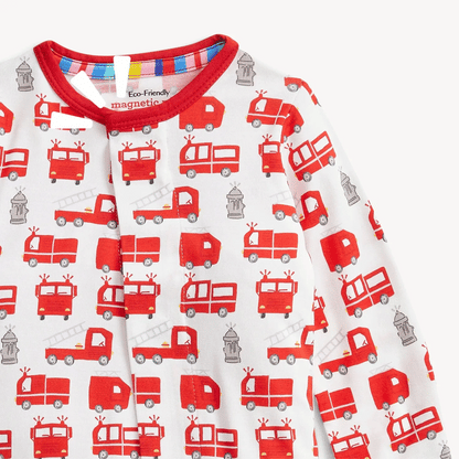 The Magnetic Me "Fired Up" Footie by Magnetic Me is a red and white baby modal sleeper featuring a playful pattern of fire trucks, ladders, and fire hydrants. The collar is trimmed in red with a striped detail on the inner neckline. This long-sleeved footie is made from eco-friendly materials and includes convenient magnetic closures for easy changes.