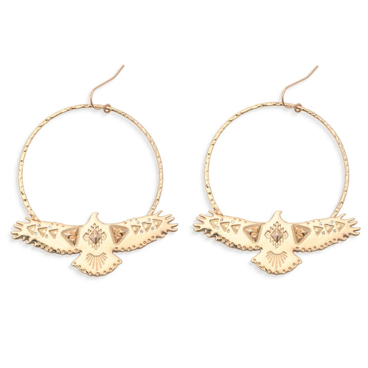 Leslie Curtis Montana Earrings by Leslie Curtis: Gold hammered hoop earrings adorned with intricately detailed, eagle-shaped pendants featuring outstretched wings and etched patterns, showcased against a white background. Ideal for those searching for standout eagle earrings with unique craftsmanship—handle with care to preserve their lasting beauty.