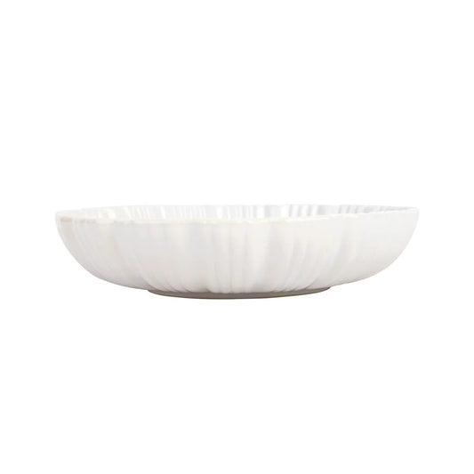 The Vietri Bari White Shallow Serving Bowl by Vietri is a white, shallow ceramic bowl featuring a slightly fluted, textured exterior. Both dishwasher safe and microwave safe, this serving bowl is photographed against a plain white background.