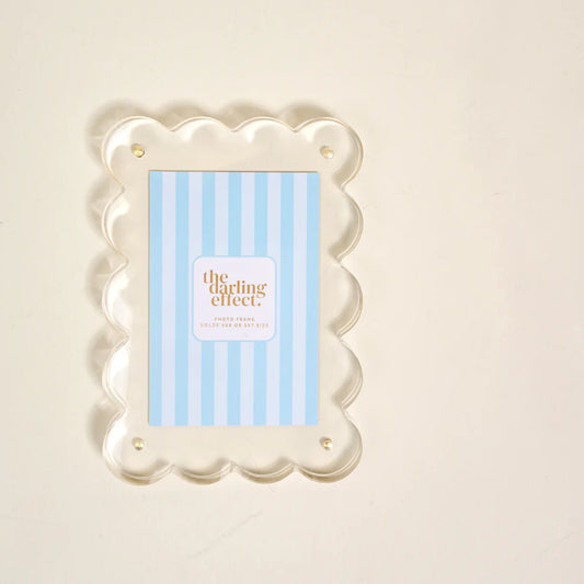 The Darling Effect Rectangle Scalloped Acrylic Frame in clear acrylic with scalloped border and brass fasteners
