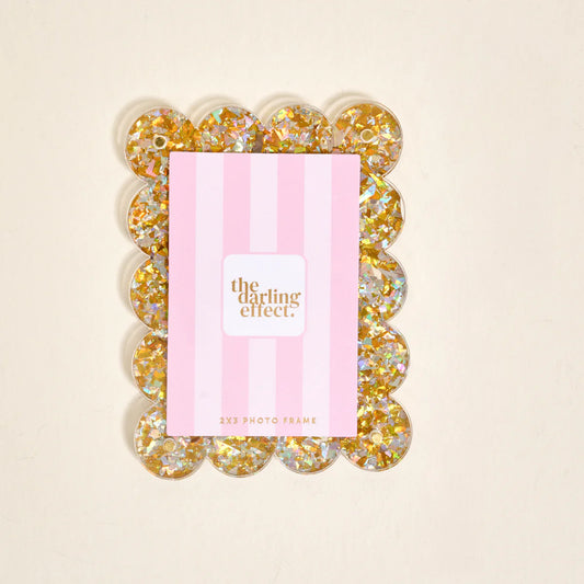 The Darling Effect Mini Acrylic Picture Frame Magnet in gold glitter with scalloped edges and pink striped insert, front view