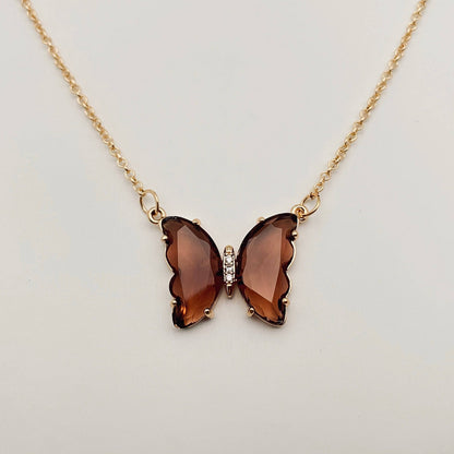 Mio Queena - Multicolor Glass Butterfly Pendant Necklace by Mio Queena, showcased on a plain, light background and designed as hypoallergenic jewelry, features a shimmering glass pendant with multicolor faceted wings resembling gemstones and a delicate row of clear stones in the center.