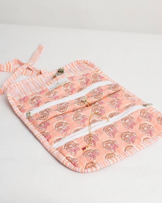 The Royal Standard Layla Quilted Jewelry Roll in pink opened to show jewelry compartments with pear print lining
