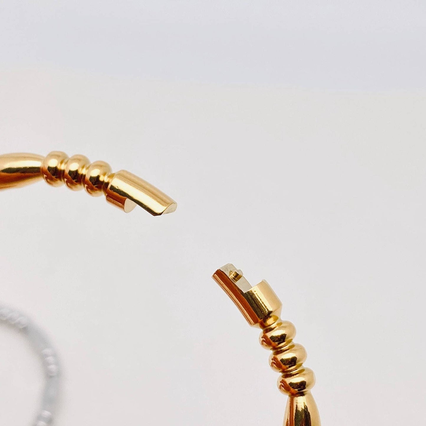 A detailed close-up of the Mio Queena Multi-style 18K Gold-plated Stainless Steel Bangle (FGS) showcases its elegant beaded design and open clasp against a simple, light backdrop—an exquisite accessory by Mio Queena, ideal for gifting.