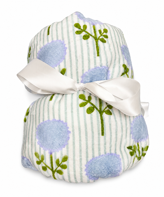 The Laura Park Marigold Ticking Stripe Blue Fleece Blanket by Laura Park Designs is a soft, cozy fleece blanket featuring green stripes and blue flower patterns, rolled up and tied with a wide white satin ribbon.