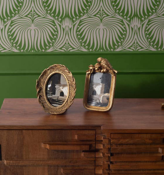 Gold polyresin feather oval frames 4x6 in. standing on wooden dresser in landscape setting