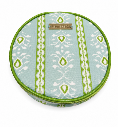 Laura Park Designs' Laura Park Rosemary Stripe Blue Jewelry Case is a round zippered pouch featuring green, white, and light blue symmetrical shapes and stripe patterns on the fabric, accented with a metallic rectangular label on top.