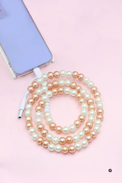 The 42POPS - Beaded Dual USB Fast Charging Cable by 42POPS, featuring alternating pearl and gold beads, is shown connected to a lavender smartphone on a light pink background—blending style with universal compatibility for all your devices.