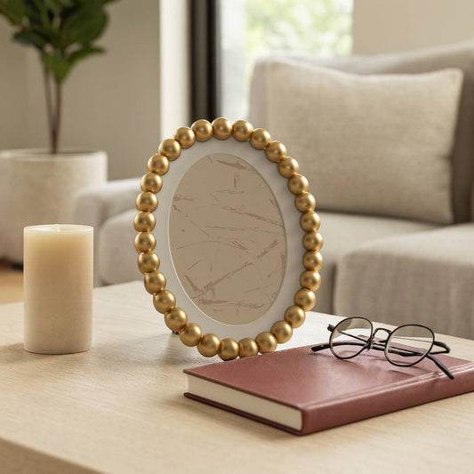 Sagebrook Home gold round beaded glass frame, oval mat, standing on table with candle and book