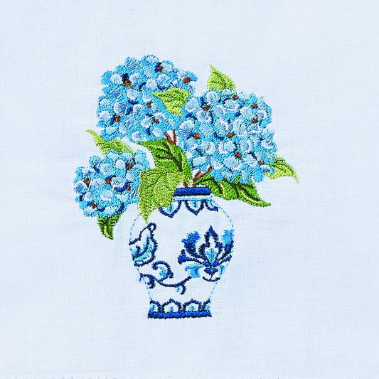 Close-up detail of embroidered blue hydrangea flowers and blue-and-white decorative vase on towel