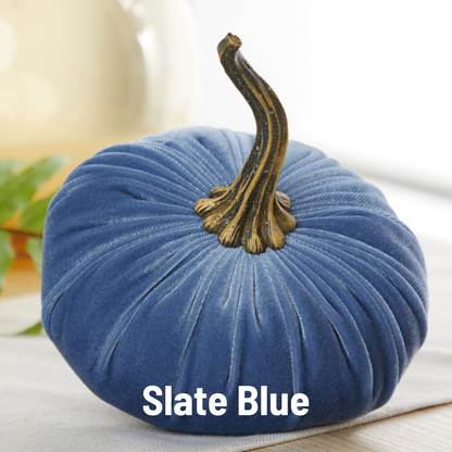 A large velvet pumpkin from Your Heart’s Content in a beautiful slate blue fabric, featuring a realistic brown stem, rests on a white surface—making it perfect for your fall mantel or Halloween table. The words “Slate Blue” appear at the bottom of the image.