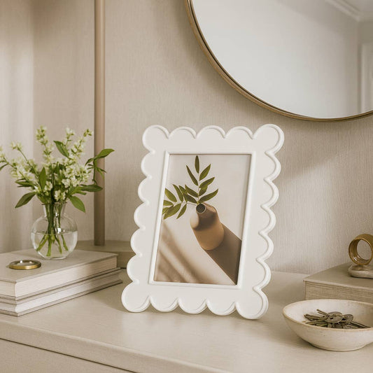 Sagebrook Home white resin photo frame with scalloped edges displayed on cream dresser with botanical decor