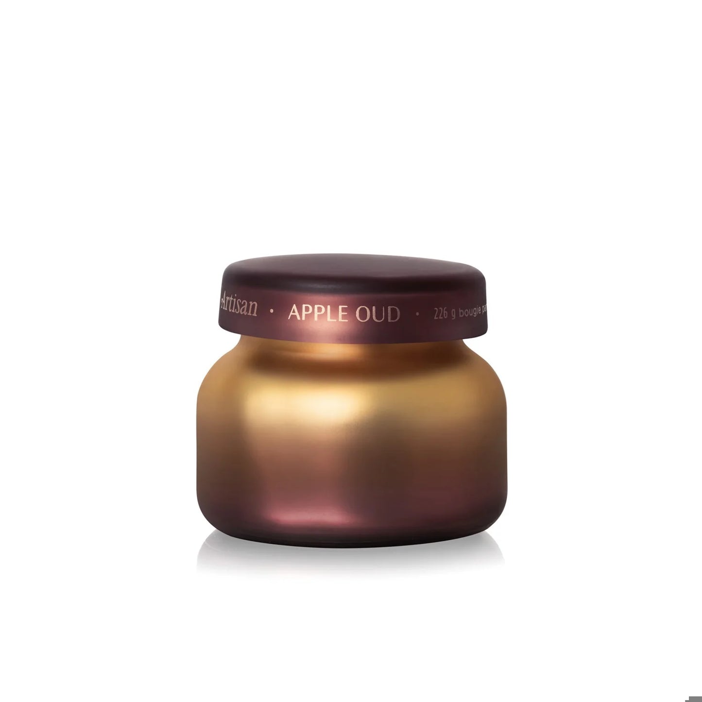 The Capri Blue Apple Oud Radiance Petite Candle by Capri Blue features a round, metallic gradient jar with a matching lid and is showcased against a white background. This elegant candle offers a layered scent experience reminiscent of Tuscan Radiance.