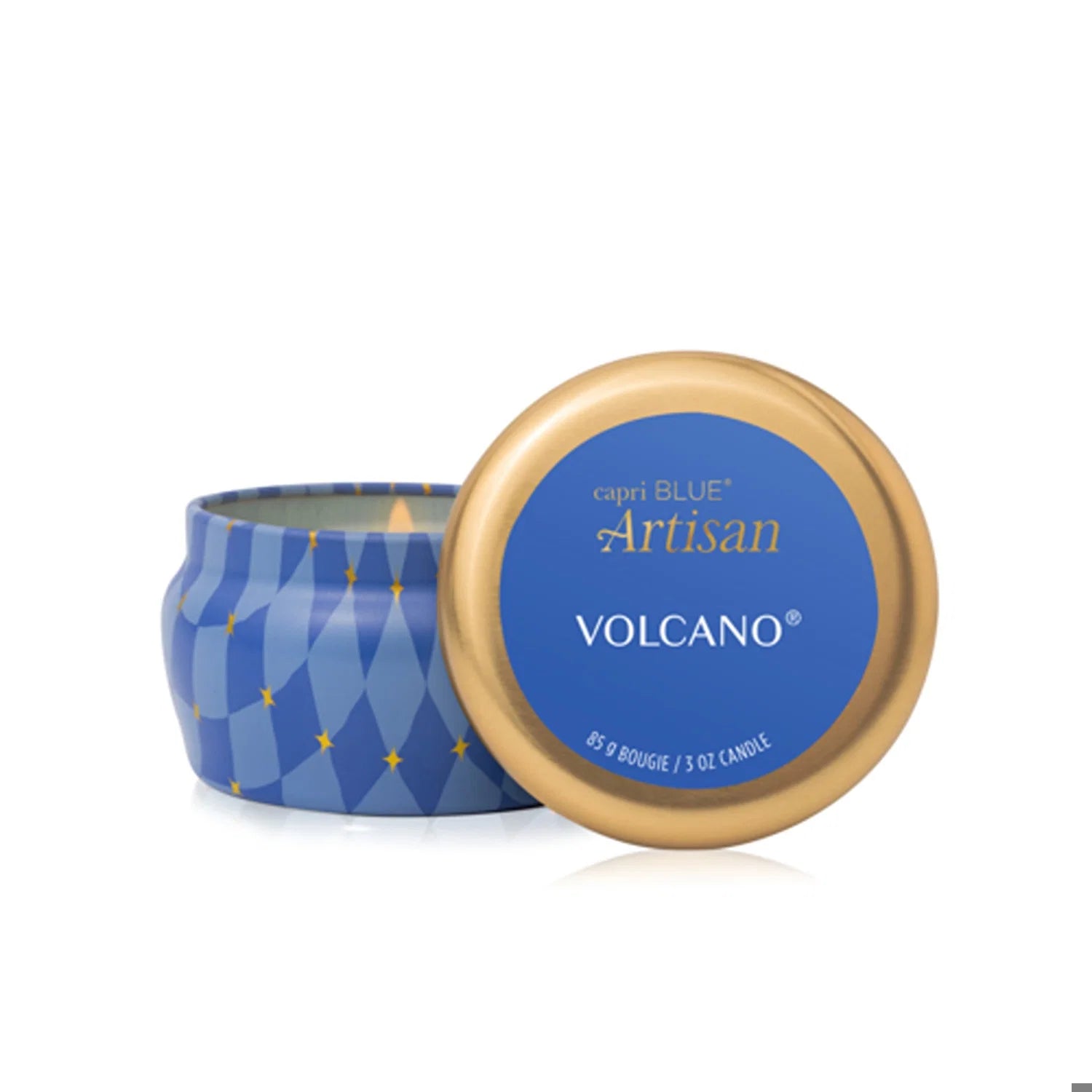 A blue and gold round scented tin labeled “Capri Blue Volcano Winter Bazaar Mini Tin Candle,” with the lid partially removed to reveal the artisan candle inside. The tin is decorated with a diamond pattern and small yellow stars, reflecting the signature Capri Blue style.