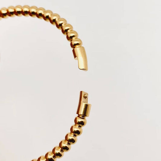 A close-up of the Mio Queena - 4mm Beads Gold Plated Stainless Steel Snap Bangle by Mio Queena, featuring an 18K gold plated beaded design with an open clasp, displayed against a plain white background—perfect for adding a touch of elegance to your jewelry gift collection.