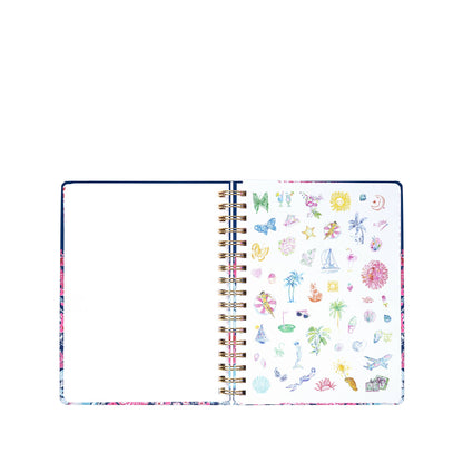 Open spiral notebook with a blank left page and colorful small drawings of flowers, shells, palm trees, and other beach-themed objects on the right page, reminiscent of the playful designs featured in the Lilly Pulitzer by Lifeguard Press Jumbo 17 Month Agenda, "In All Her Glory.