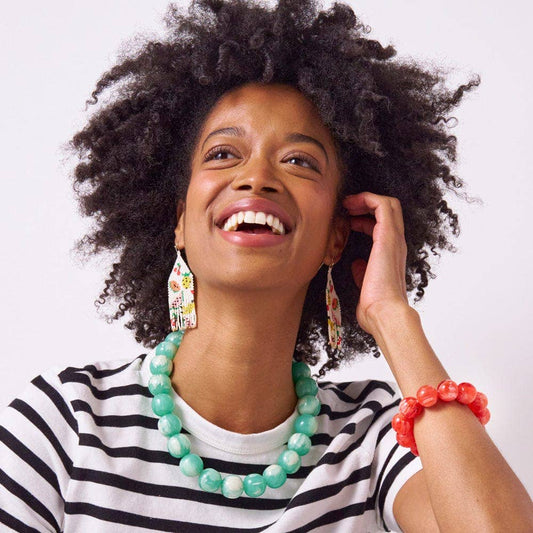 Person wearing INK + ALLOY Iris aqua necklace with striped shirt and matching beaded bracelet