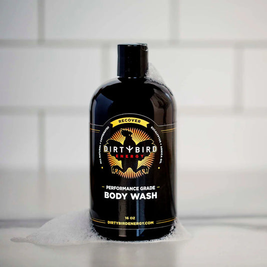 Dirty Bird 16 oz black performance grade body wash bottle with gold and yellow circular label and white soap foam