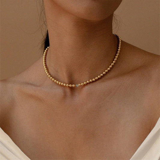 JOSSLYN by wall to wall gold beaded necklace worn on neck, showing 18K stainless steel spheres