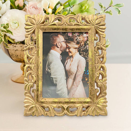 Gold ornate wood picture frame displaying couple's wedding photo, styled with flowers