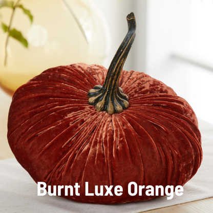 An extra large velvet pumpkin from Your Heart’s Content in a rich burnt orange hue, featuring a lifelike stem, rests gracefully on a table—an ideal choice for an elegant wedding centerpiece. The phrase “Burnt Luxe Orange” is displayed at the bottom.
