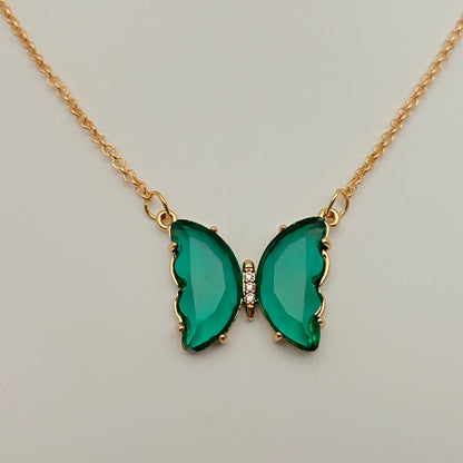 The Mio Queena - Multicolor Glass Butterfly Pendant Necklace by Mio Queena features delicate green gemstone wings and sparkling clear stones at its center. Displayed on a neutral background, this elegant necklace is crafted as hypoallergenic jewelry, making it perfect for sensitive skin.