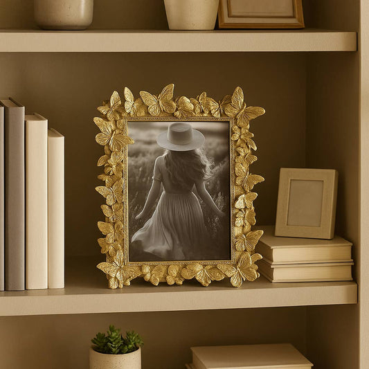 Sagebrook Home gold butterfly polyresin frame 5x7 holding black and white photo on bookshelf with neutral décor