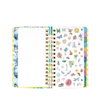An open Lilly Pulitzer by Lifeguard Press - Medium 17 Month Agenda, Lovely Lilly, featuring colorful tabs and pages; the left page is blank with a partial blue floral motif, while the right page displays an array of vibrant summer-themed stickers—ideal for brightening up your 2026-2027 planner or adding a stylish touch to your Lilly Pulitzer agenda.