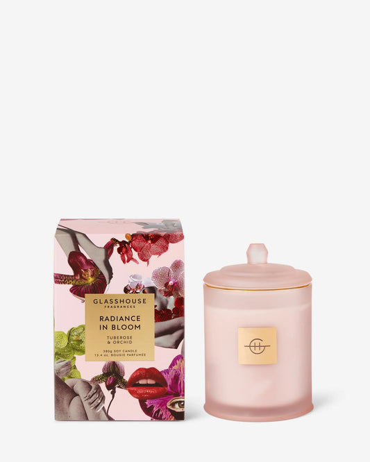 Glasshouse Radiance in Bloom 13.4oz Mother's Day candle in blush pink glass jar with lid beside floral patterned box