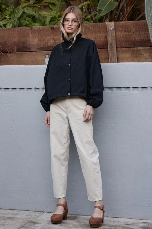 Raisonnel High Neck Button-up Jacket in black, worn with cream pants, full-length side view