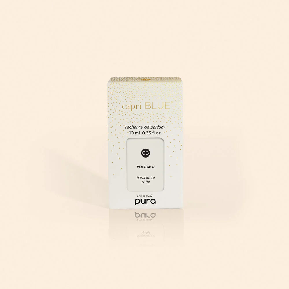 A white and gold box labeled “Capri Blue” featuring the “Volcano Pura Holiday Diffuser Refill” for Pura devices, containing 10 ml (0.33 fl oz), is displayed against a light beige background. Infused with Capri Blue’s signature Volcano fragrance, this refill delivers vibrant notes of tropical fruits and sugared citrus.