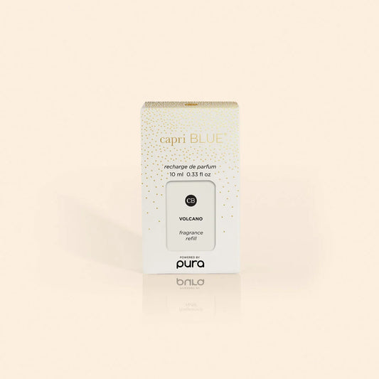 A white and gold box labeled “Capri Blue” featuring the “Volcano Pura Holiday Diffuser Refill” for Pura devices, containing 10 ml (0.33 fl oz), is displayed against a light beige background. Infused with Capri Blue’s signature Volcano fragrance, this refill delivers vibrant notes of tropical fruits and sugared citrus.