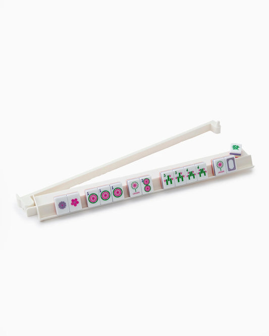 The Oh My Mahjong White Rack & Pusher Set by Oh My Mahjong stylishly displays eight Mahjong tiles featuring assorted floral and bamboo patterns, with a green die neatly placed at one end. Perfect for elevating your game night, this set pairs effortlessly with acrylic racks or mahjong pushers to enhance your playing experience.