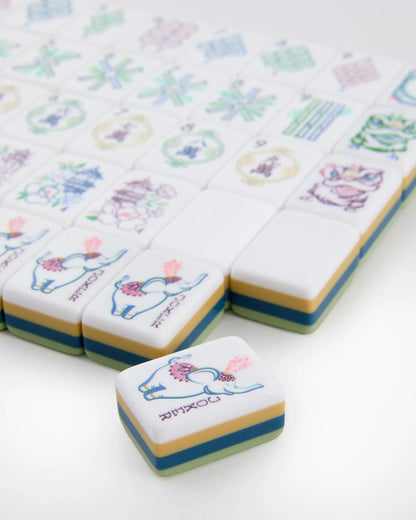 A close-up of the elegant Oh My Mahjong Willow Tiles set by Oh My Mahjong, with most tiles arranged in rows and one tile—adorned with a colorful elephant illustration—placed prominently in the foreground, distinct from the others.