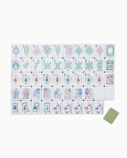 A full set of Oh My Mahjong Willow Tiles by Oh My Mahjong is elegantly arranged in rows, displaying circles, bamboos, characters, flowers, seasons, and “NEWS” wind tiles. In this decorative arrangement, one green tile is set apart at the bottom right.