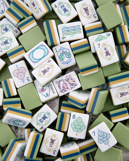 A collection of Oh My Mahjong Willow Tiles by Oh My Mahjong, featuring various symbols and numbers in shades of green, white, and yellow, are scattered and overlapping one another in the image.